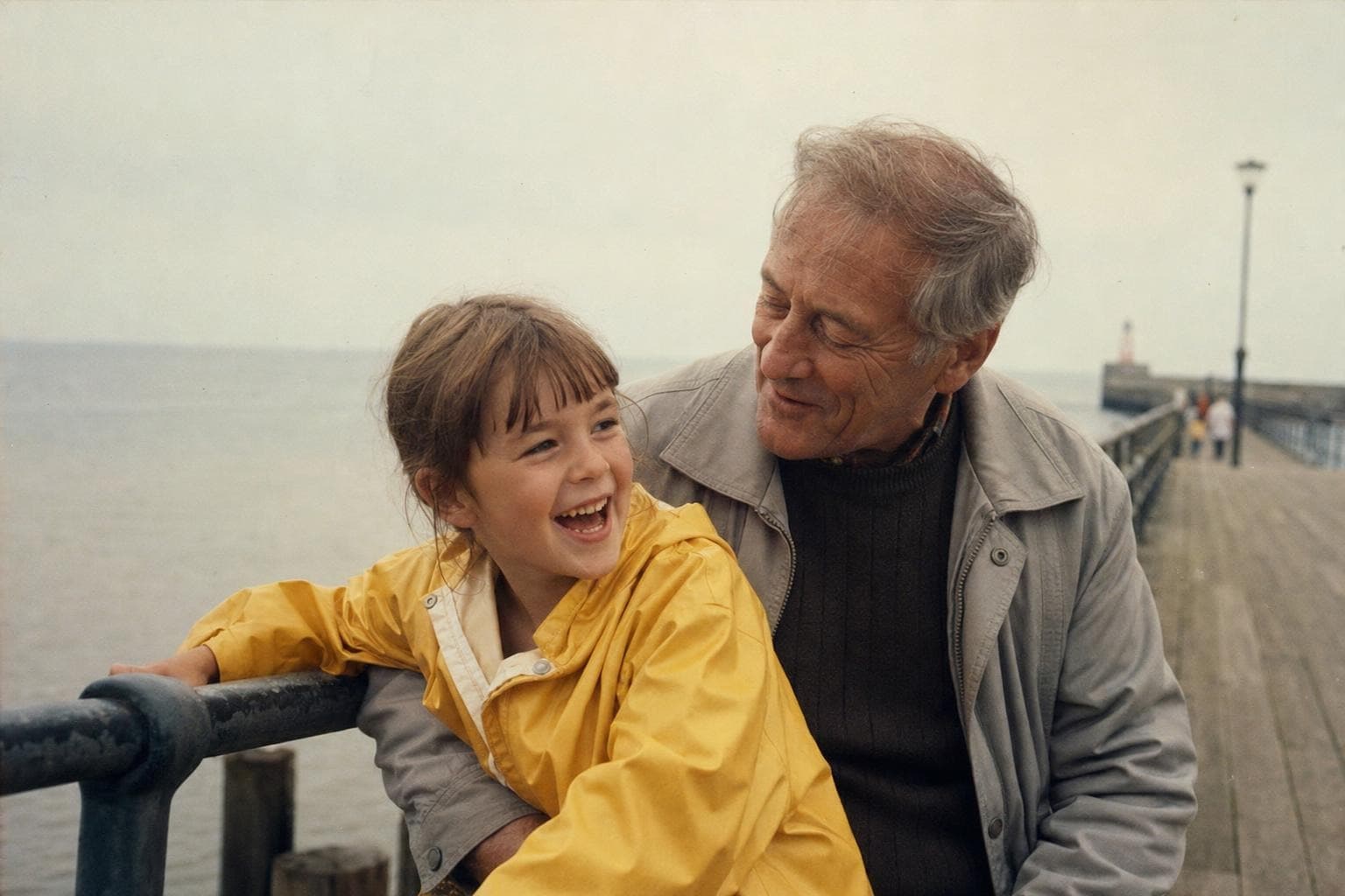 A restored family video frame showing a grandfather and granddaughter by the sea